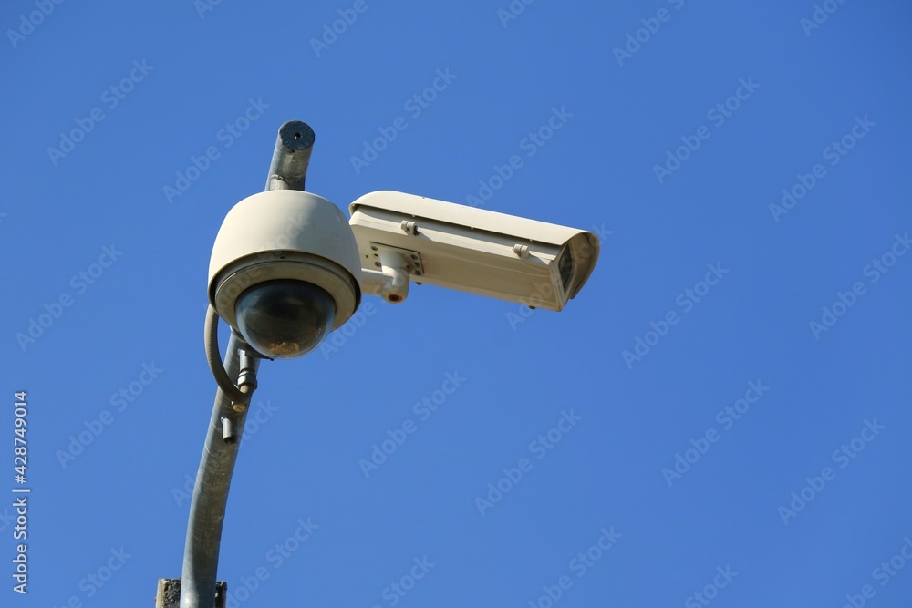 CCTV Security camera at public street in the city with blue sky background. Technology and outdoor concept. CCTV Security camera at public street in the city with blue sky background. Technology and outdoor concept.