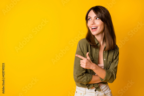 Portrait of pretty cheerful person look indicate finger empty space proposition isolated on yellow color background