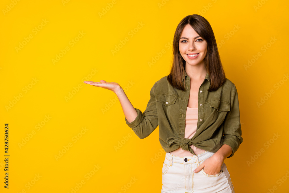Portrait of adorable cheerful person beaming smile arm palm hold show product isolated on yellow color background Portrait of adorable cheerful person beaming smile arm palm hold show product isolated on yellow color background