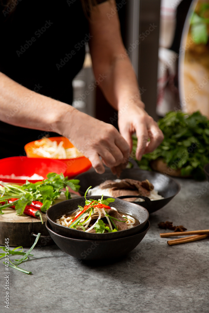 Food stylist putting finishing touch to Vietnamese beef pho