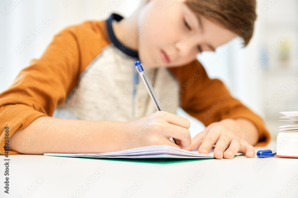 children, education and learning concept - student boy with book writing to notebook at home children, education and learning concept - student boy with book writing to notebook at home