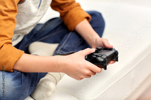 leisure  technology and people concept - boy with gamepad playing video game at home