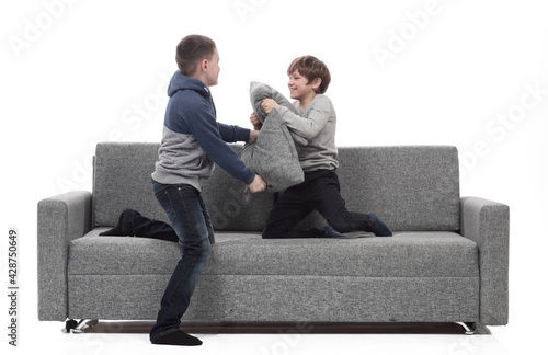 two brothers have a pillow fight on the couch. © ASDF