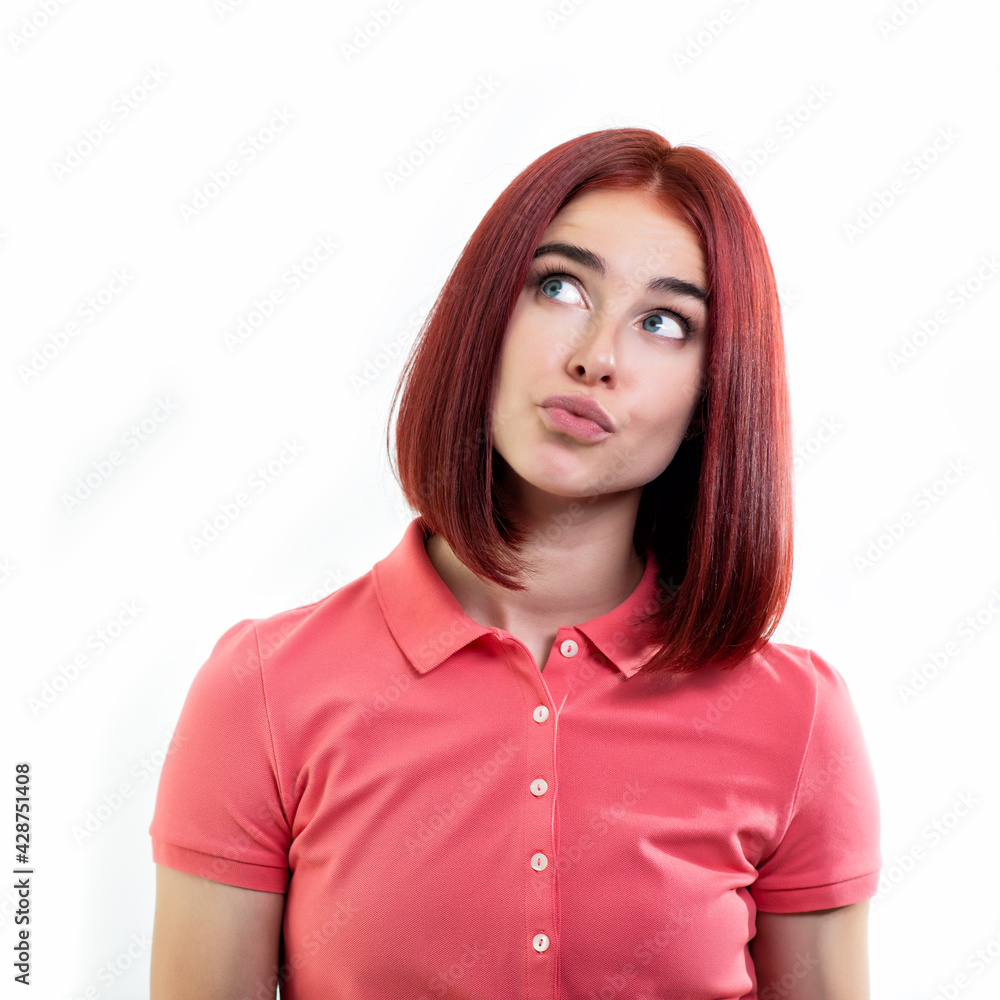 Charming young ginger woman thinks, dreams, makes plans for the future over white background looking left and up at copyspace. Charming young ginger woman thinks, dreams, makes plans for the future over white background looking left and up at copyspace.