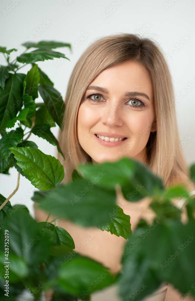 Beautiful calm middle aged woman with green plant, natural light. Anti-aging and beauty treatment. Beautiful calm middle aged woman with green plant, natural light. Anti-aging and beauty treatment.