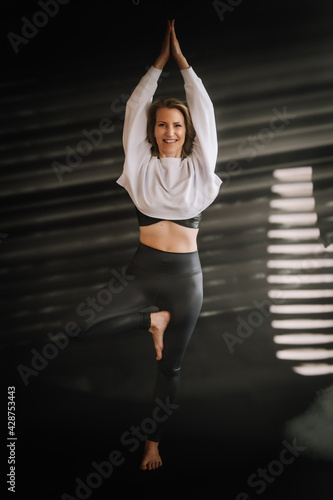 Frau macht Yoga entspannt, kraftvoll, Balance, Üben, Fitness, dunkler Hintergrund, Lichteinfall, Nebel, Der Baum, Tree pose, Vrksasana