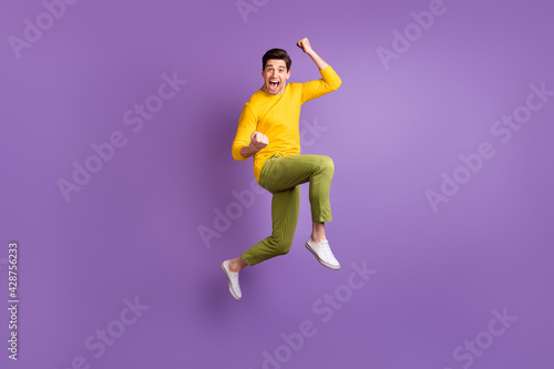 Full size photo of young happy excited crazy positive smiling man jumping in success victory isolated on violet color background © deagreez