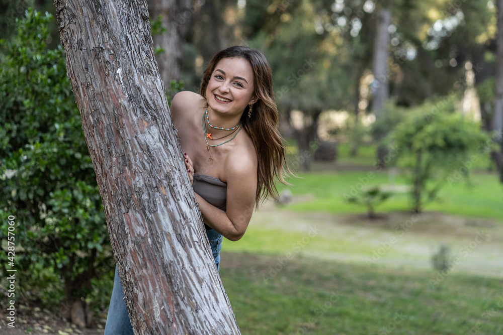 Portrait of a pretty  young Caucasian woman posing behind a tree