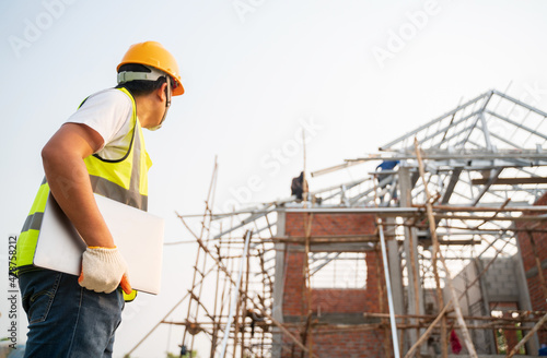 Engineering Consulting People on construction site holding notebook computer in his hand. Home building inspector. Construction site check drawing and business workflow of new structure building
