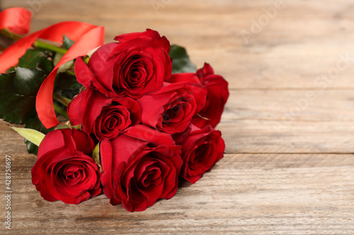 Beautiful red roses on wooden table  space for text. Valentine s Day celebration
