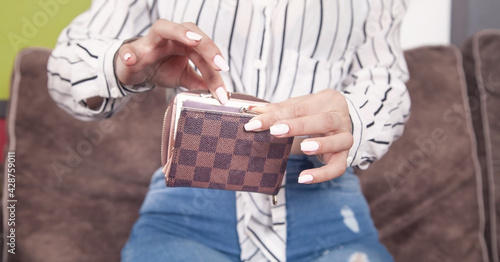Young woman holding brown wallet at home.