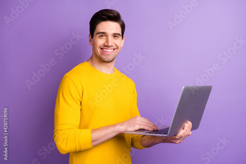 Portrait of satisfied young person toothy smile hands hold netbook isolated on purple color background