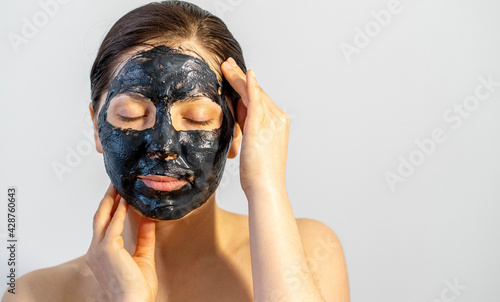 Woman relaxing with black charcoal facial mask