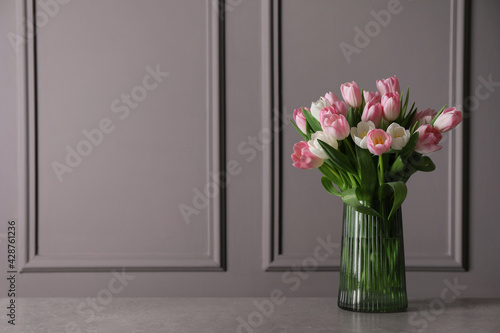 Beautiful bouquet of tulips in glass vase on grey table. Space for text #428761236