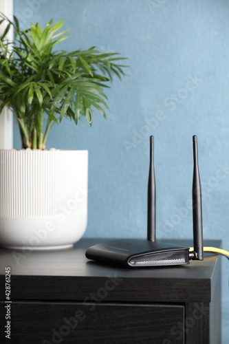 Obraz na plátně Modern Wi-Fi router near blue wall indoors