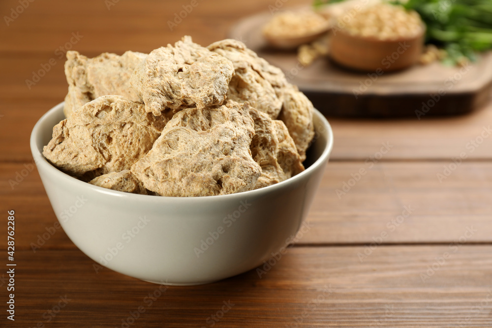 Dehydrated soy meat chunks in bowl on wooden table, closeup Dehydrated soy meat chunks in bowl on wooden table, closeup