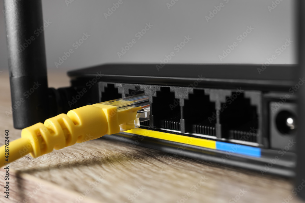 Connected cable to router on wooden table, closeup. Wireless internet communication Connected cable to router on wooden table, closeup. Wireless internet communication