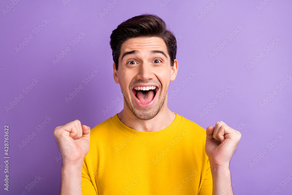 Photo of astonished guy fists up celebrate open mouth yell yeah isolated on pastel violet color background Photo of astonished guy fists up celebrate open mouth yell yeah isolated on pastel violet color background