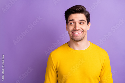 Photo of satisfied young man toothy smile look empty space wear yellow outfit isolated on violet color background