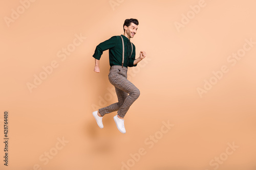 Full length profile side photo of young man jump up run empty space sale hurry isolated on beige color background