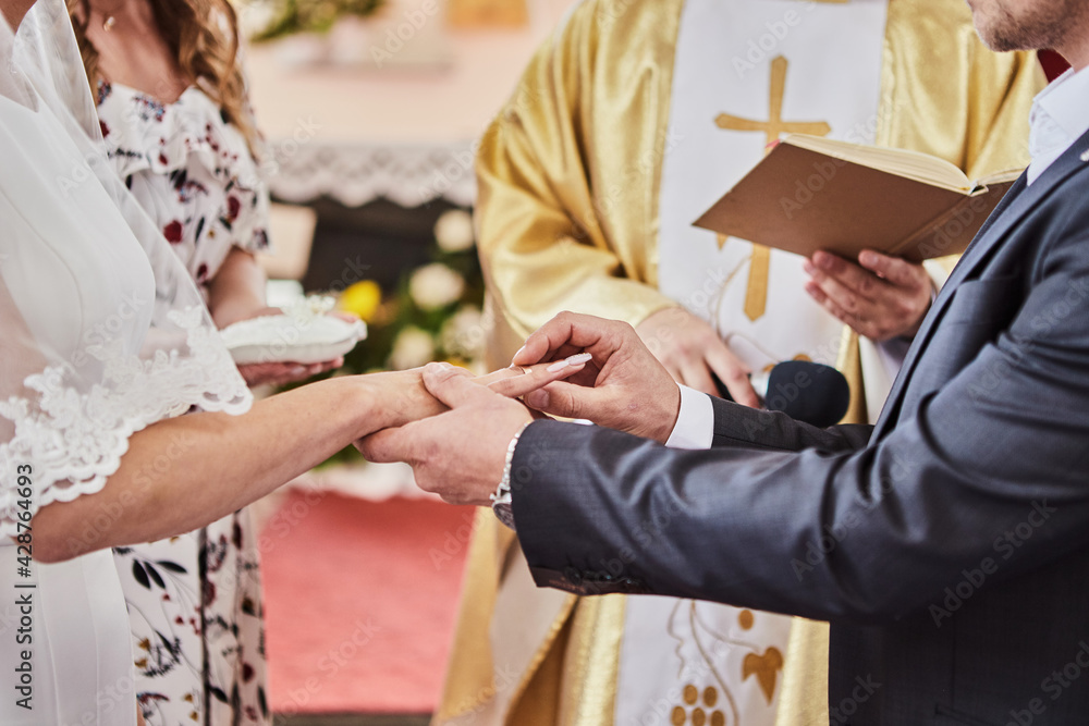Obraz premium Newlyweds exchange rings during a wedding in a Catholic church