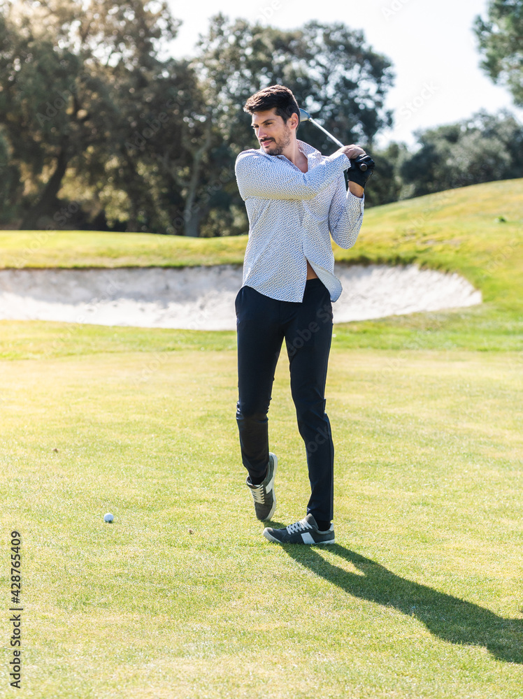 A young Caucasian male playing golf on a professional golf course A young Caucasian male playing golf on a professional golf course