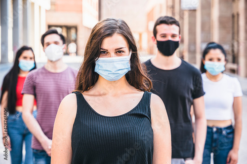 Portrait of a multiracial group of friends with masks in protection from Coronavirus infections, Covid-19 - Leader woman with other millennials behind her with serious eyes looking into camera smile