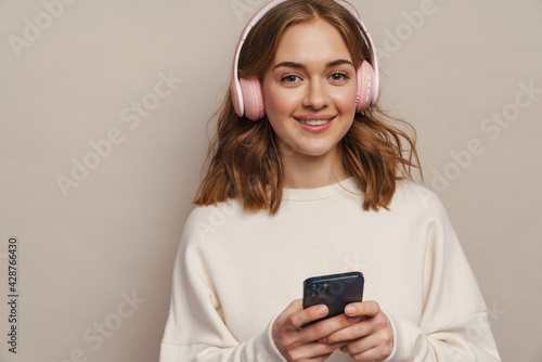 Young smiling woman listening music with headphones and cellphone