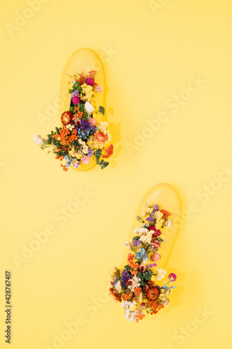 Yellow sneaker on a yellow background filled with flowers. Flat lay. Spring minimal abstract modern koncept.