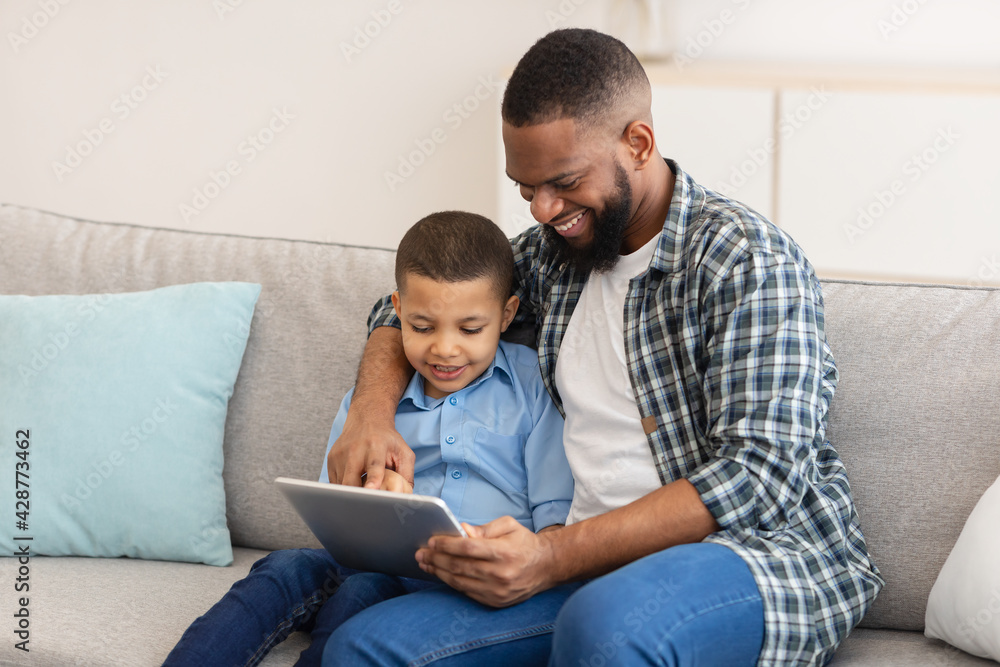 African Daddy And Little Son Using Tablet Together At Home African Daddy And Little Son Using Tablet Together At Home