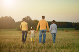 Happy family on wheat field in sunny day.  back view