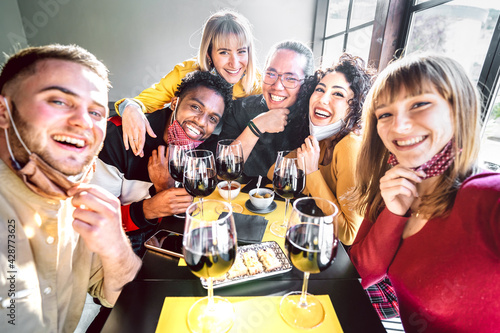 Friends taking selfie at winery with open face mask - People having fun together drinking red wine glasses at restaurant reopening - Selective focus on middle guys and girls with warm contrast filter