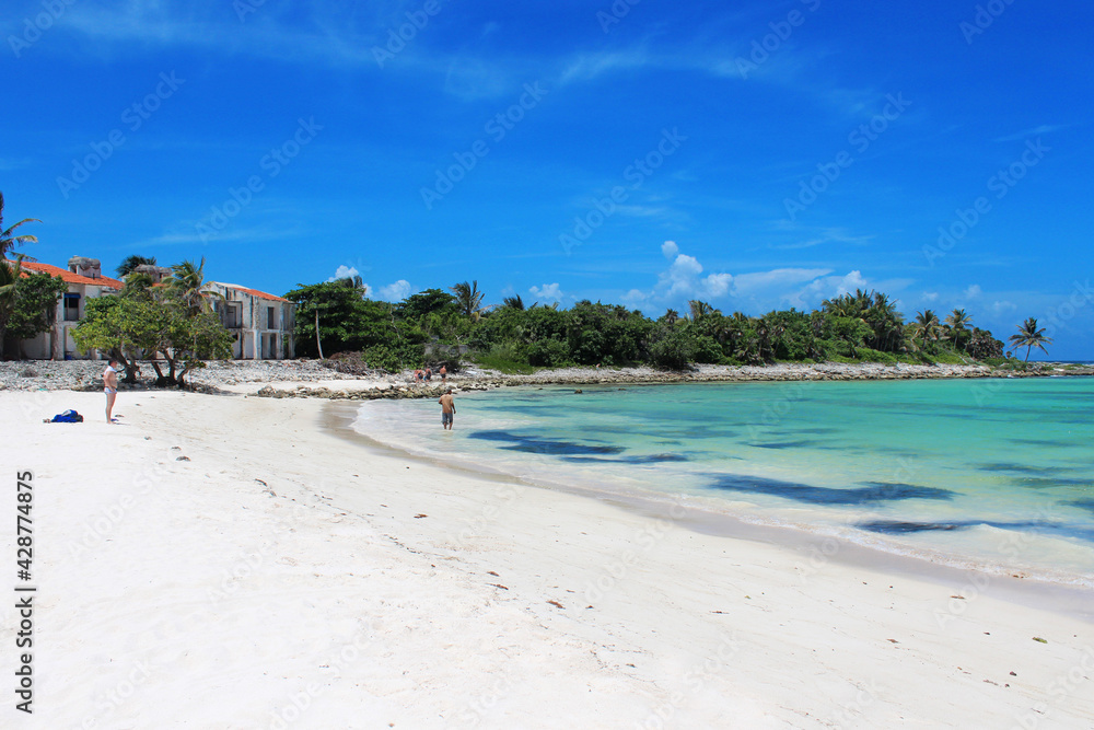 Beautiful white sandy beach with palm trees and turquoise waters of Caribbean sea in summer sunny day. Caribbean coast in the Playa del Carmen, Riviera Maya, Quintana Roo, Mexico. Soft focus