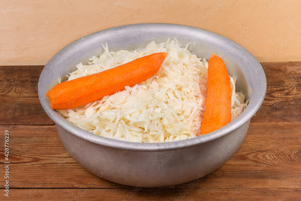 Shredded white cabbage and whole carrots in large mixing bowl Shredded white cabbage and whole carrots in large mixing bowl