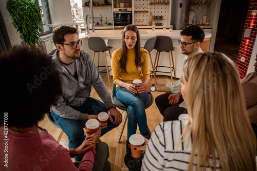 Diverse group of people sitting in circle in group therapy session.