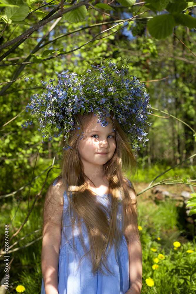 Preschool girl with a wreath of forest forget-me-nots on her head Preschool girl with a wreath of forest forget-me-nots on her head