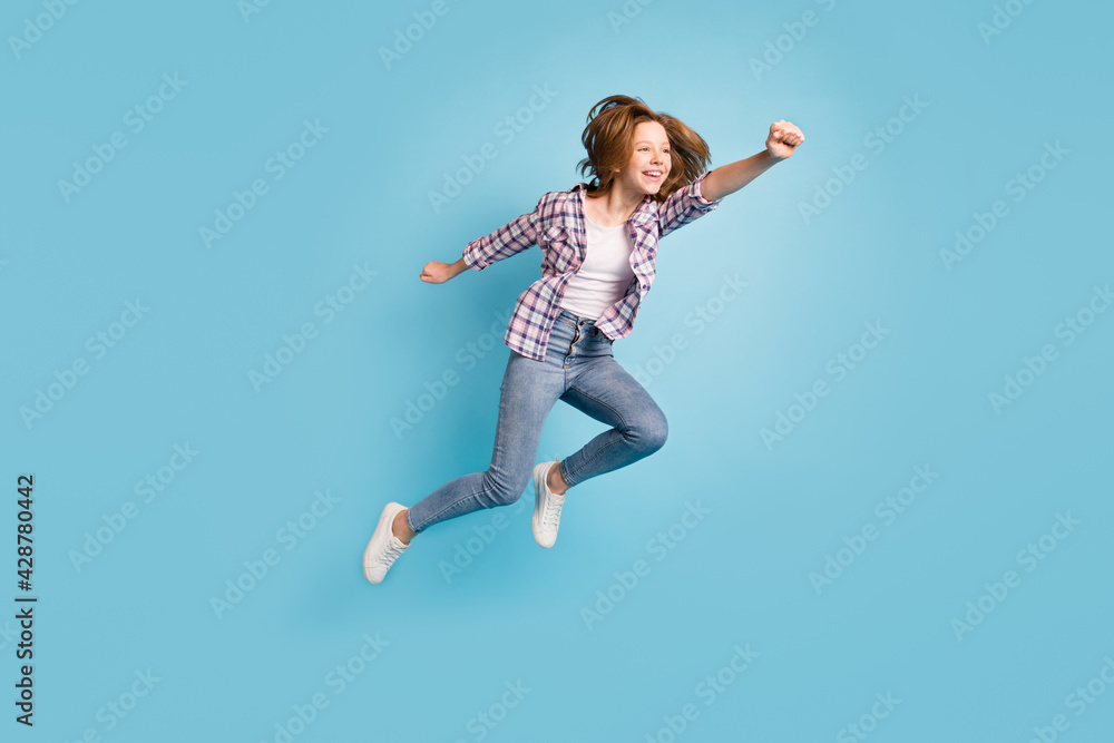 Full length profile portrait of carefree kid raise fist flying look empty space isolated on blue color background