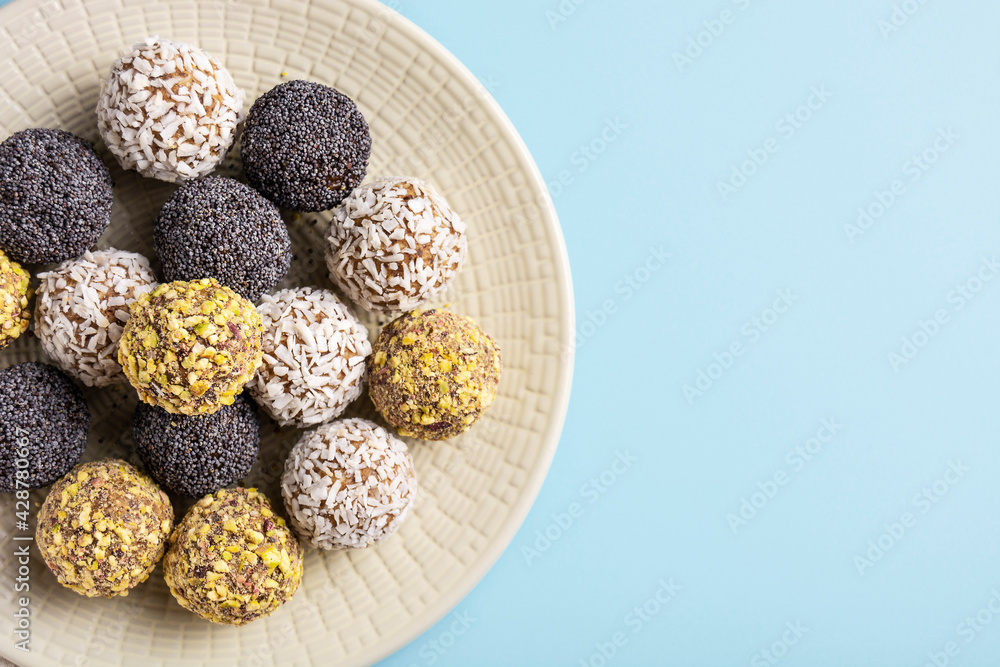 Healthy energy balls of dried fruits and nuts lie on a large plate on a blue background, horizontal orientation, flat lay, copy space, close-up Healthy energy balls of dried fruits and nuts lie on a large plate on a blue background, horizontal orientation, flat lay, copy space, close-up