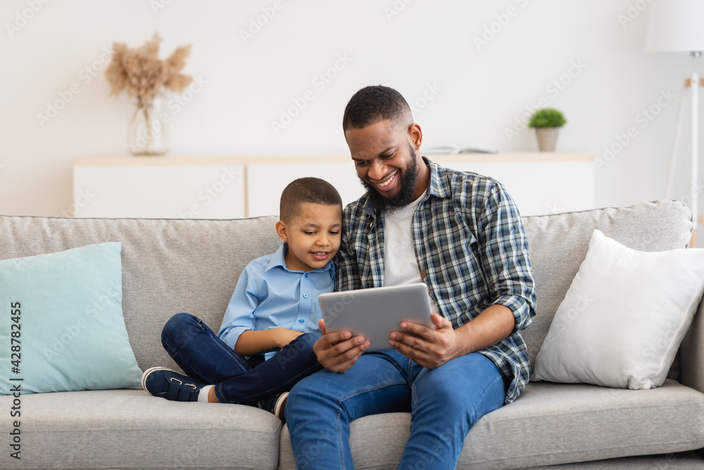 Dad And Son Watching Cartoons On Tablet Online At Home