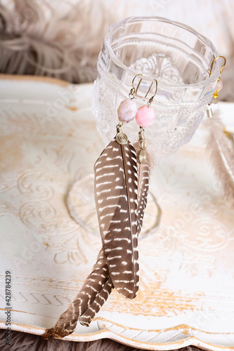 Feather and pink opal stone earrings on romantic bright background