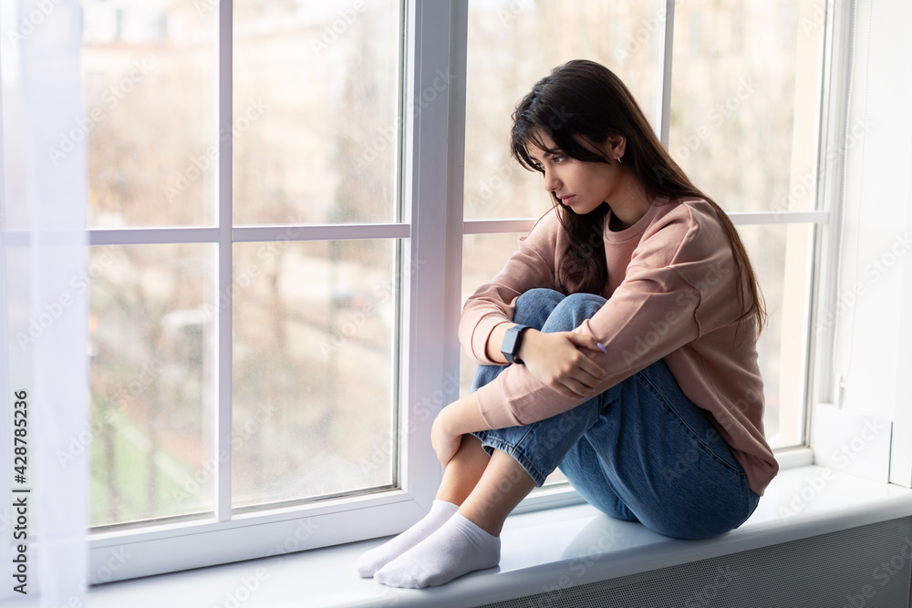 Sad woman looking out of window at home Sad woman looking out of window at home
