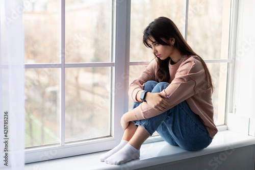 Sad woman looking out of window at home