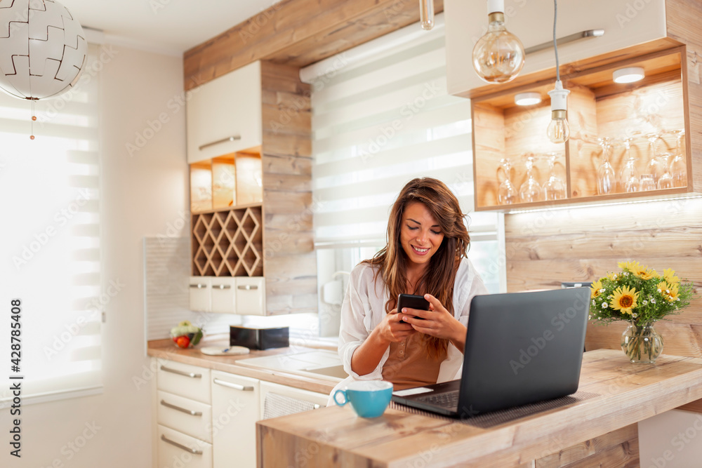 Woman using smart phone and laptop while telecommuting Woman using smart phone and laptop while telecommuting