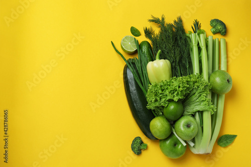 Fresh green vegetables on yellow background, space for text photo