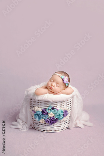 Newborn girl on a violet background. Photoshoot for the newborn.  A portrait of a beautiful newborn baby girl	