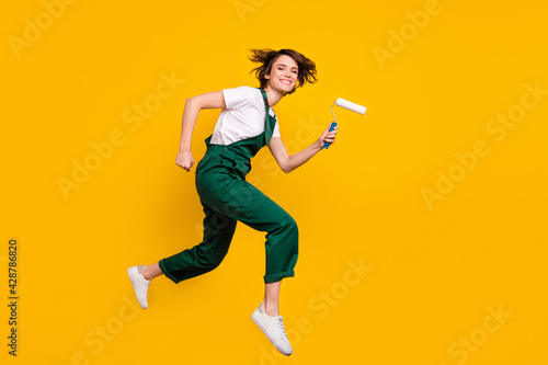 Full size profile side photo of happy positive smiling woman painter running fast speed isolated on yellow color background