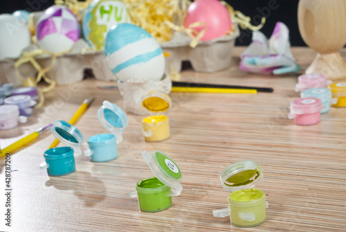 Multicolored paints and Easter eggs on a wooden table. Sets for coloring Easter eggs.