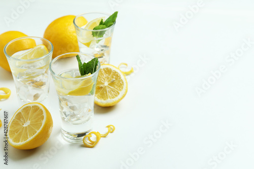 Foto Shots of vodka and lemons on white background
