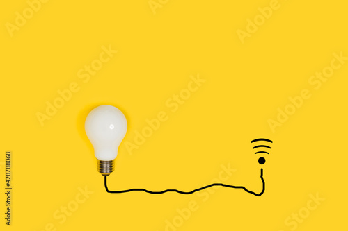 Una bombilla blanca sobre un fondo amarillo liso y aislado. Vista superior. Copy space. Concepto de comunicación inalámbrica. photo