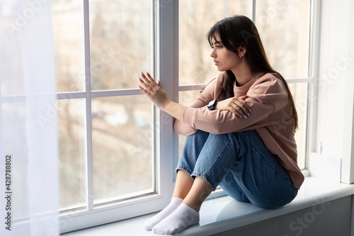 Sad woman looking out of window at home